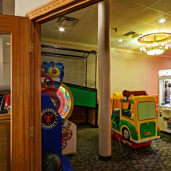 A restaurant's arcade room with various games, including claw machines and a kiddie ride.