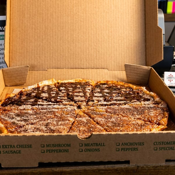 A dessert pizza with chocolate and powdered sugar in a Larry's Pizza box on a counter.