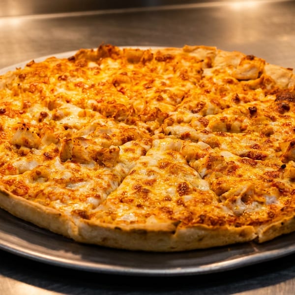 A whole buffalo chicken pizza, cut into slices, on a metal tray.