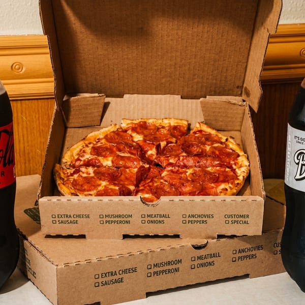 A pepperoni pizza in a cardboard box, flanked by a Coca-Cola Zero Sugar and Barq's Root Beer.