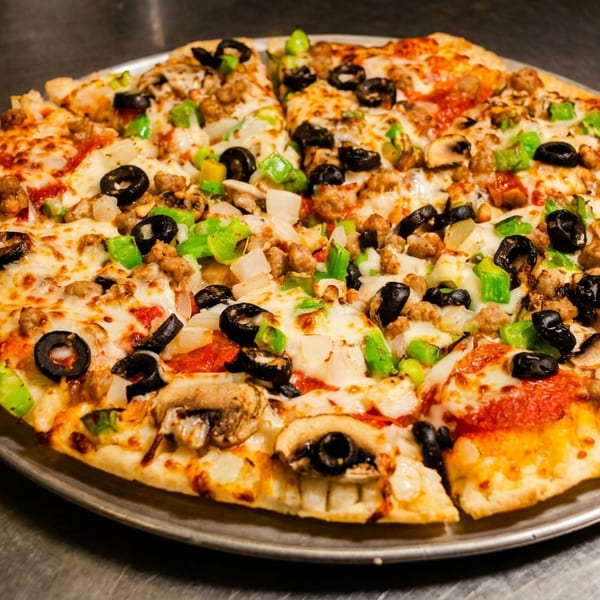 A freshly baked pizza with sausage, olives, green peppers, onions, and mushrooms on a metal tray.
